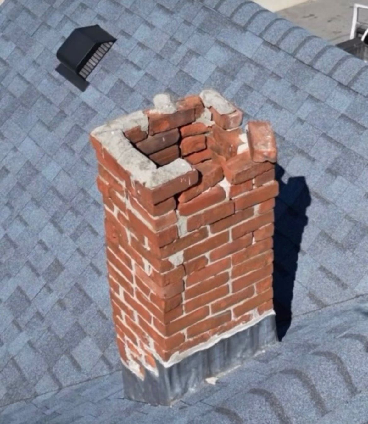 Cracked, crumbling chimney crown and spalling brick in need of masonry repair