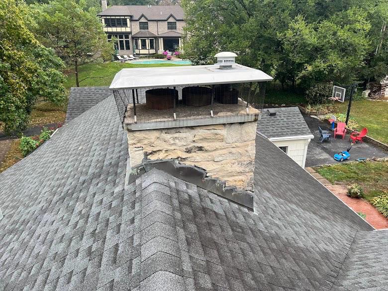Stone chimney with torn, separated flashing where it meets the roofline